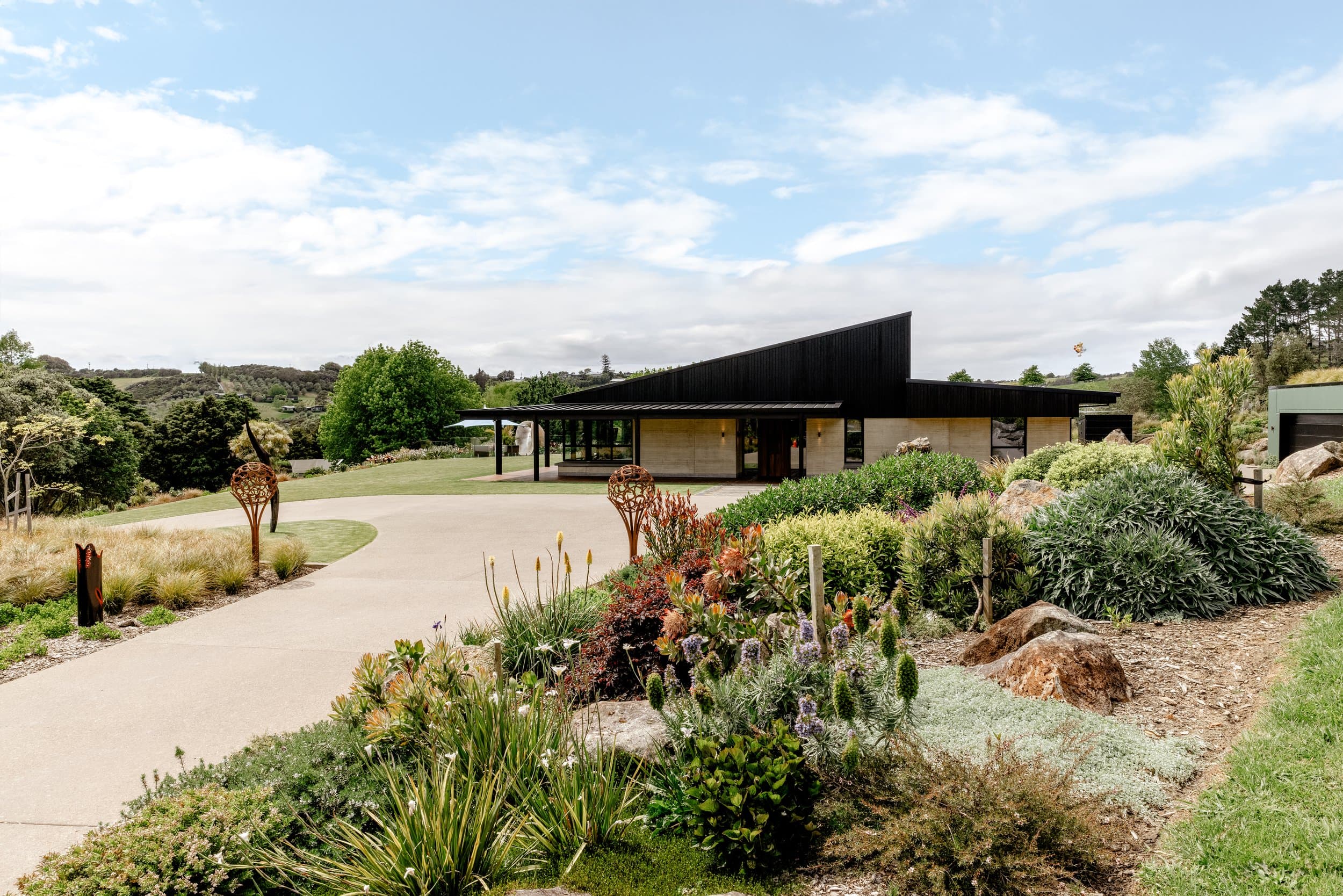 Matakana house with a low black roof and landscaped approach